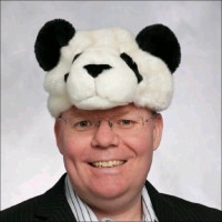 Smiling man wearing a panda hat against a neutral background.